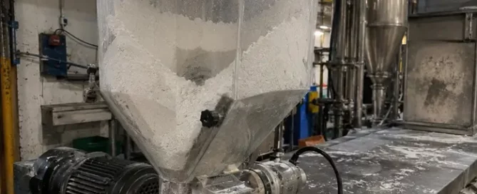Calcium carbonate powder bridging inside a transparent feeder hopper on a polypropylene compounding line.