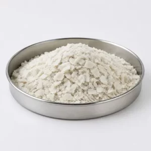 Irregular white recycled polymer flakes in a stainless steel sample dish