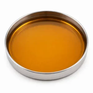 Amber rubber process oil in a shallow stainless steel sample dish